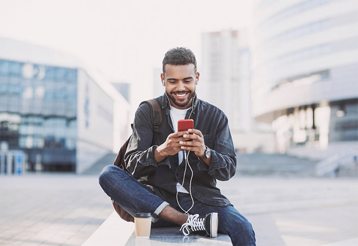 Man sitting on phone outside listening to music.
