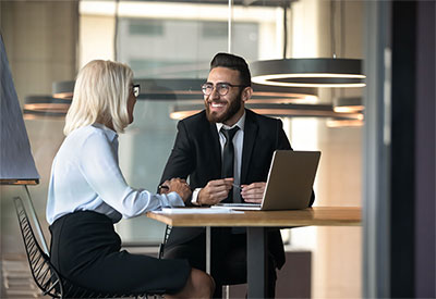 2 business people laughing at a small table.